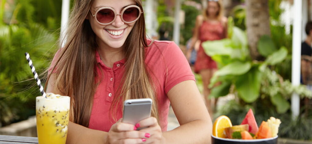 Jovem feliz vendo o instagram da pousada em celular